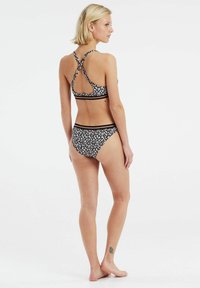 Bikini a stampa floreale nera con design incrociato sulla schiena. Presenta una texture morbida e bande elastiche in vita e sulle spalline, evidenziando una silhouette aderente.