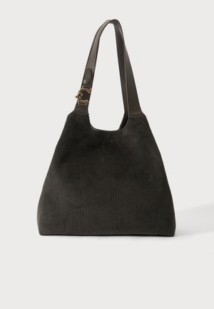 Sac à main en velours côtelé noir avec une large bandoulière en cuir et un détail de boucle métallique dorée sur un fond clair uni.