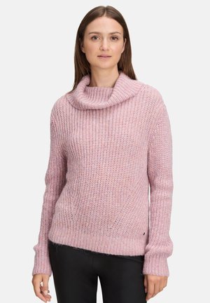 Roze gebreide trui met een col, voorzien van een textuurpatroon en verlaagde schouders. Geschreven met zwarte aansluitende broek.