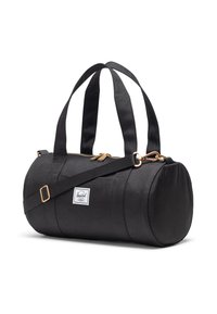 Borsa da viaggio cilindrica nera con doppie maniglie superiori, tracolla regolabile, zip dorata e un'etichetta bianca con logo Herschel sul lato.