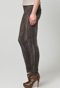 Tajta jeans i en brun och svart marmorering, tillverkade av denim, med medelhög midja och åtsittande ben, kombinerat med bronsfärgade klackskor.