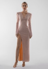 Garas rozā kleitas ar teksturētu rakstu, V veida izgriezumu, garām piedurknēm un augstu sānu šķēlumu. Ir pūkainas plecu detaļas un atbilstoša auduma aksents.