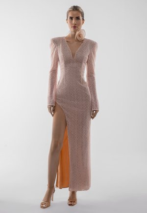 Garas rozā kleitas ar teksturētu rakstu, V veida izgriezumu, garām piedurknēm un augstu sānu šķēlumu. Ir pūkainas plecu detaļas un atbilstoša auduma aksents.