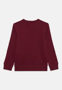 Sweatshirt bordeaux à manches longues, avec des poignets côtelés et un col rond. Matériau en coton doux avec une texture lisse. Aucun logo ou motif visible.