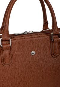 Borsa a mano in pelle marrone con texture, manici doppi, accessori in argento e chiusura a zip superiore. Dettaglio circolare del logo sulla parte anteriore.
