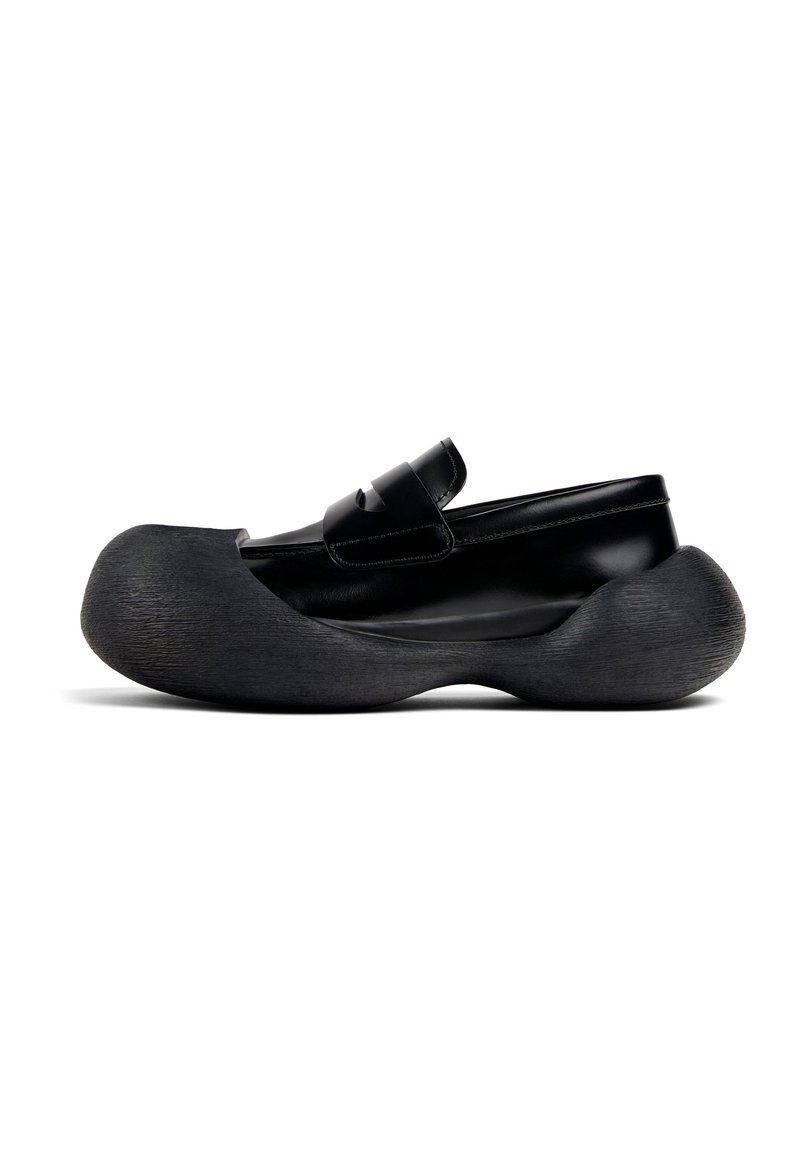 Scarpa nera stampata con suola oversize texturizzata e tomaia in pelle liscia. Presenta una cinghia regolabile sul collo del piede.