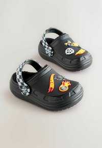 Black rubber clogs with checkered strap, featuring colorful decals of cars and flames. Soft inner lining for comfort. Textured sole.