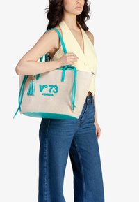 Borsa tote in paglia intrecciata con accenti turchesi, dotata di dettaglio con nappina e logo ricamato. Forma rettangolare con doppi manici.