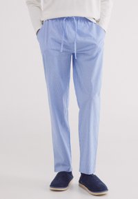 Pantaloni lounge a righe blu chiaro con vita elastica e cordoncino, dotati di tasche laterali e una vestibilità comoda. Abbinati a pantofole blu navy.