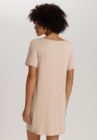 Abito a maniche corte in beige chiaro, caratterizzato da un collo rotondo, una texture morbida e una vestibilità rilassata che termina sopra il ginocchio.