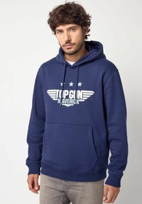 Felpa blu navy in cotone, con tasca a marsupio frontale e stampa grafica con stelle. Chiusura con lacci sul cappuccio.