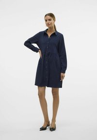 Marineblauwe hemdjurk met lange mouwen, knoopsluiting aan de voorkant en een geplooid taille. Vormgegeven in soepele stof, met twee zijzakken en een subtiele glans.