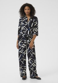 Black and white patterned outfit with blue accents; features a button-up shirt, wide-leg pants, and a tied waist. Smooth fabric with a relaxed fit.