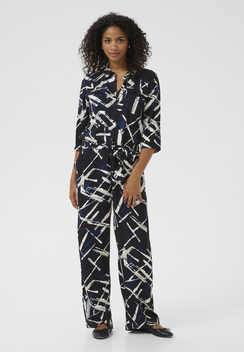 Black and white patterned outfit with blue accents; features a button-up shirt, wide-leg pants, and a tied waist. Smooth fabric with a relaxed fit.