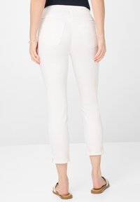 Witte cropped broek met een gladde textuur, voorzien van achterzakken en een getailleerd ontwerp. De zoom heeft kleine zijnsplits.