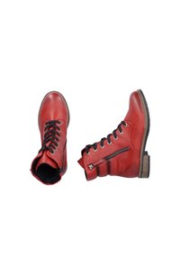 Bottes chelsea rouges en cuir avec des lacets noirs et une fermeture éclair sur le côté. Caractéristiques d'une pointe arrondie et d'une semelle texturée pour une meilleure adhérence. Design de botte classique.