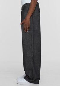 Tumed denim cargo püksid sirge lõikega, küljetaskuga ja hästi istuva vöökohaga. Kanda valgete tossudega; minimaalse õmblusega.