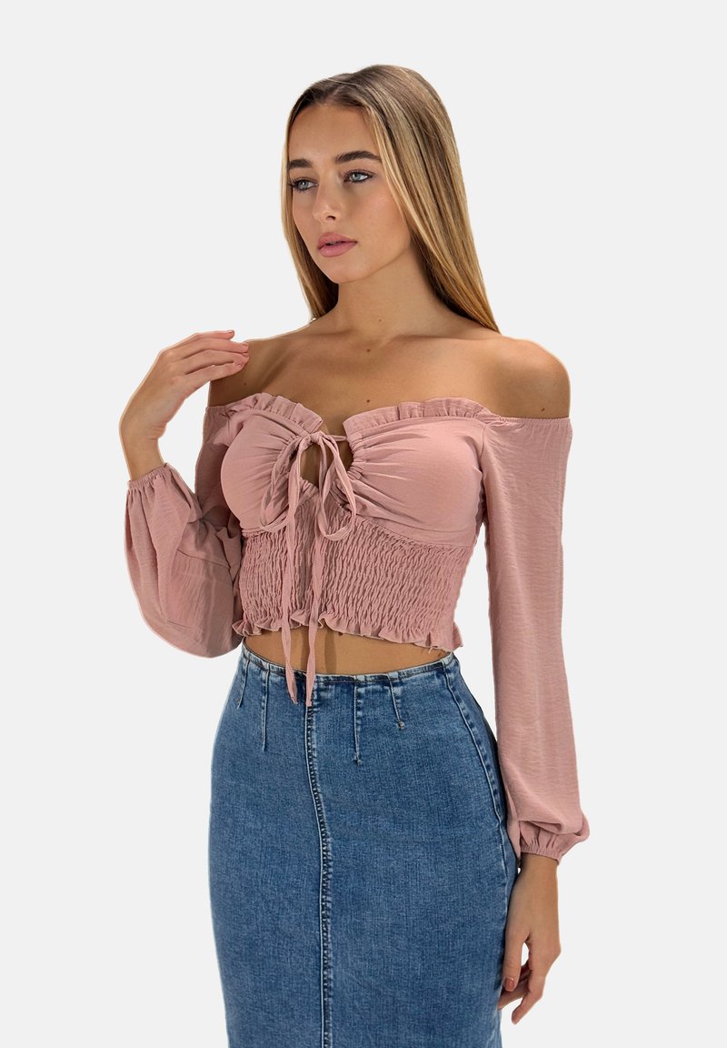 Rosa, schulterfreies, kurzes Oberteil mit fransigen Kanten, Frontbindedetail und langen Puffärmeln, kombiniert mit einem hoch taillierten Jeansrock.