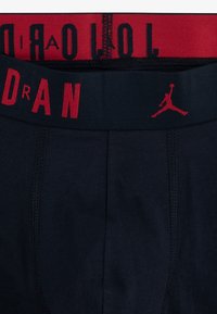 Boxer briefs neri con un elastico rosso in vita riportante il testo "JORDAN" e un logo Jumpman. Tessuto liscio con un design aderente.
