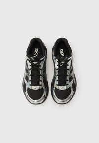 Pár černých a stříbrných běžeckých bot ASICS s černými tkaničkami, pohled shora na bílém pozadí.