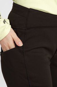 Sorte højtaljede bukser lavet af strækbart materiale med synlige syninger, der har en sidelomme med lynlås og en glat tekstur.