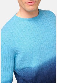 Pull en tricot à dégradé bleu avec texture côtelée, présentant un haut bleu clair se dégradant en bleu foncé en bas, col rond.