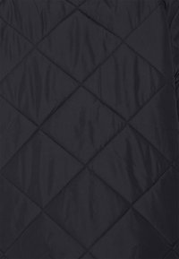 Prošívaná tmavě modrá látka v diamantovém vzoru, zdůrazňující texturu a detaily šití. Vhodná pro svrchní oděvy nebo izolační oblečení.