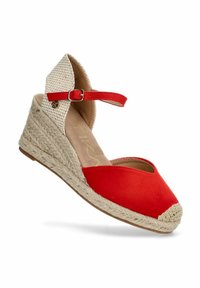 Zapato cuña de lona roja con suela de yute trenzada y tirante color crema. Presenta un ajuste de hebilla en el tobillo y un diseño de punta redonda.