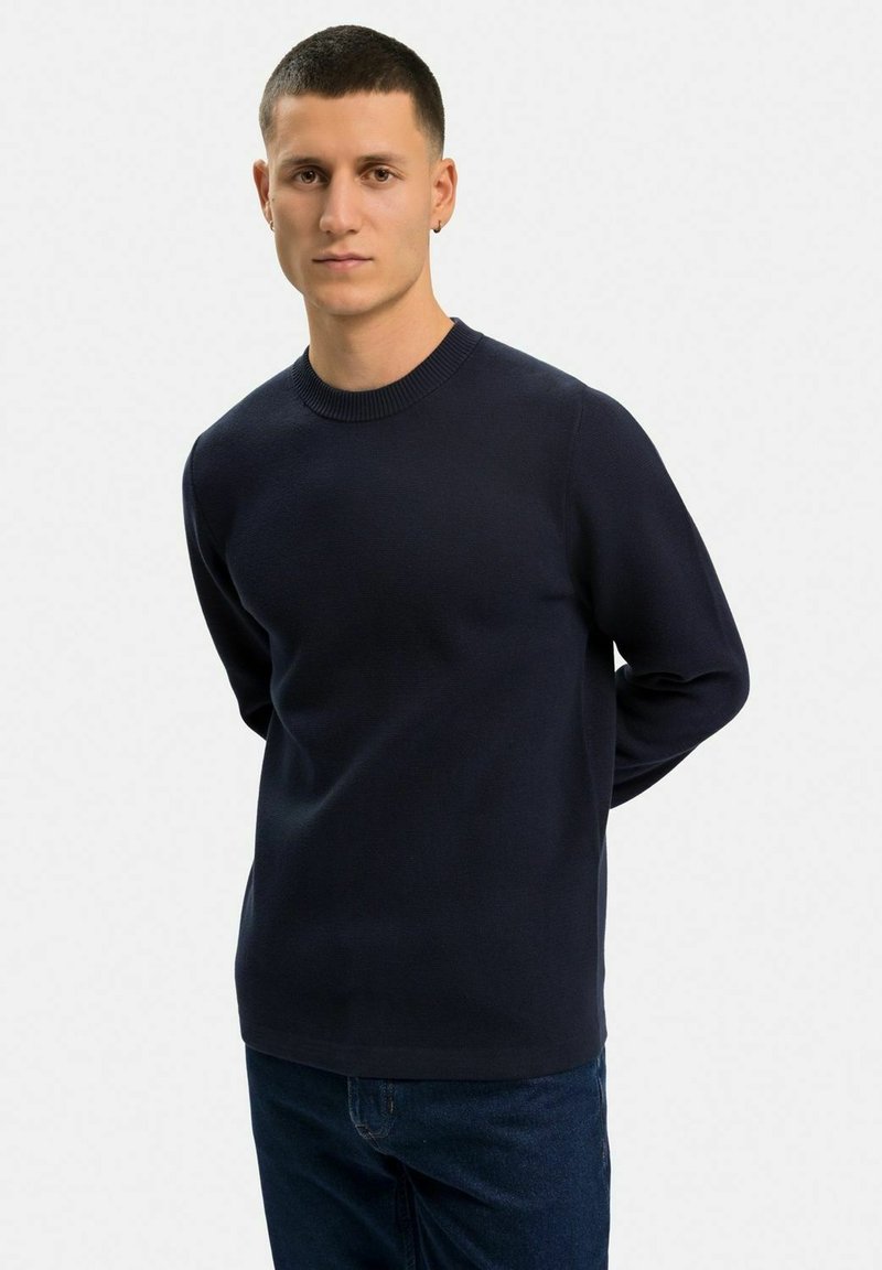 Marina blå stickad tröja med rund halsringning, långa ärmar och en slät textur. Avslappnad passform, minimalistisk design.