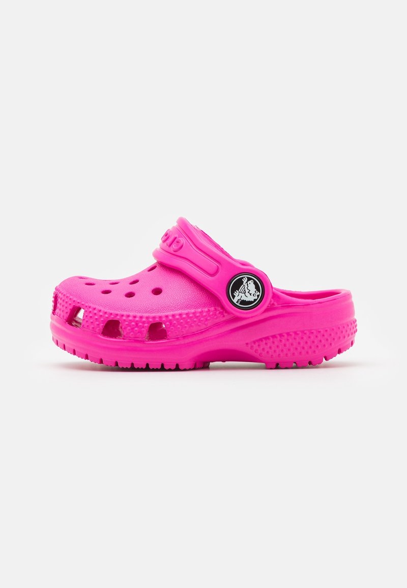 Sabot en caoutchouc rose avec des trous de ventilation, une bride arrière et une semelle texturée. Présente le logo de la marque sur le côté. Fini lisse sur l'ensemble.