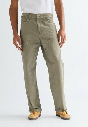 Olivengrønne bukser lavet af robust stof med lappe-lommer, forstærkede knæ og kobberfarvet hardware. Løs pasform med lige ben.