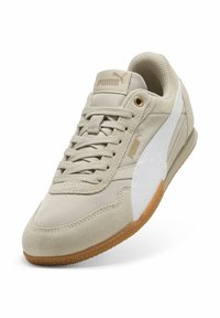 Beżowe sneakersy z zamszowej i syntetycznej cholewki, białym bocznym paskiem, teksturowanym językiem i gumową podeszwą. Zawierają logo PUMA na pięcie.