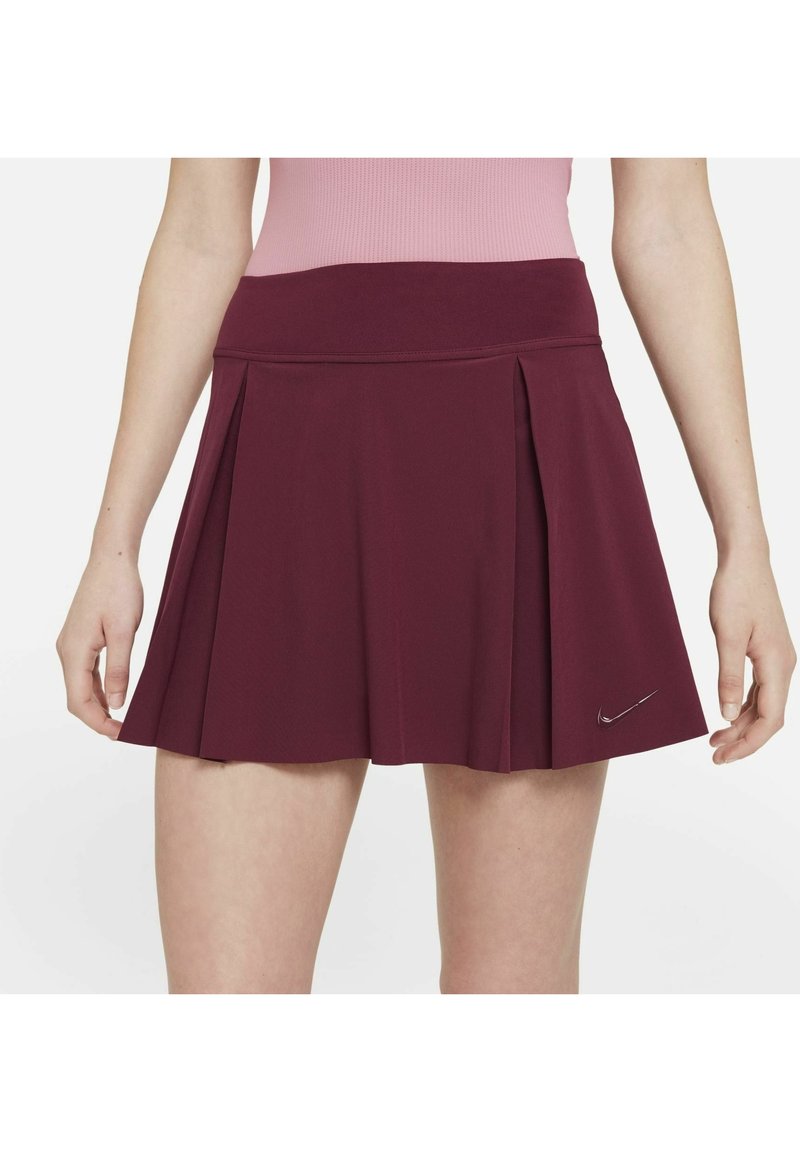 Bordeaux plissé rok van rekbare stof, met een brede tailleband en een klein, reflecterend Nike-logo aan de onderkant van de linkerkant.