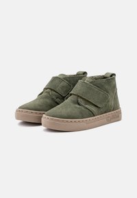 Stivaletti alla caviglia in suede verde con cinturini in Velcro, punta arrotondata e suola in gomma color beige con un motivo testurizzato e un marchio sul lato.