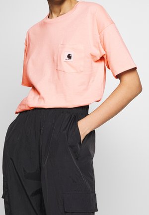 Vaaleanpunainen lyhythihainen T-paita, jossa on rintatasku logolapulla, yhdistettynä mustiin, kevyisiin cargo-housuihin, joissa on sivutaskut.