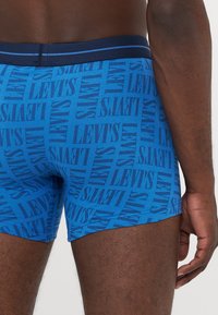 Kék boxeralsó, puha anyagból készült, amelyen a Levi's logója kerül bemutatásra. A derékpánt sötétkék, kontrasztos csíkokkal díszítve.