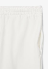Pantalones de chándal blancos hechos de una tela suave que cuentan con una cinturilla elástica y bolsillos laterales. Textura suave con un acabado elástico en la cintura.
