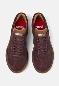 Tumman viininpunaiset lenkkarit verkkokudoksella ja nahkasuunnittelulla, joissa on ruskea kieli ja pohjalliset, joissa lukee valkoisella kirjalla "CAMPER".