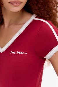 Raudonas aptemptas viršus su V formos iškirpte, balta apdaila aplink iškirptę ir rankoves, su užrašu "jets trans..." balta siuvinėjimu.