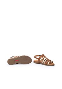 Sandalias de tiras marrones y beige con suela plana. Cuenta con material de cuero, diseño de espalda abierta y suela texturizada geométrica.