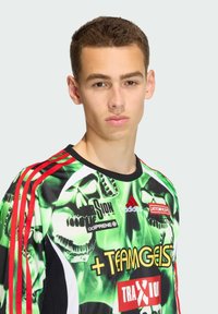 Groene grafische trui met schedelp patronen en zwarte, rode en gele accenten. Gemaakt van lichtgewicht materiaal met een ronde hals en logo-details.