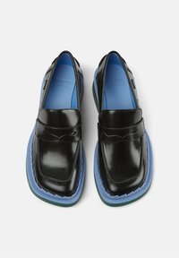 Mocassins en cuir noir avec une finition brillante, des semelles intérieures bleues et une semelle extérieure unique en couches avec des accents bleus et verts.