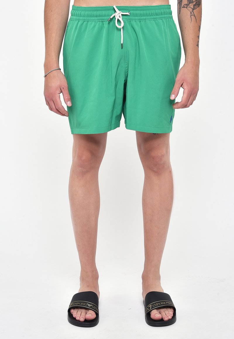 Costumi da bagno verdi con elastico in vita e cordino bianco. Presentano tasche laterali e un piccolo logo vicino all'orlo. Tessuto liscio e piatto.