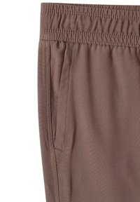 Primo piano di pantaloni marroni con vita elastica e tasca sulla cucitura laterale con dettagli di cucitura visibili.