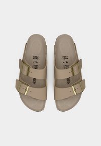 Καφέ σανδάλια με δύο λουριά, διακοσμημένα με αγκράφες σε χρυσό τόνο, με διαμορφωμένο πέλμα και μαλακή υφή στη σόλα. Μέγεθος 37 σημειωμένο στο εσωτερικό.