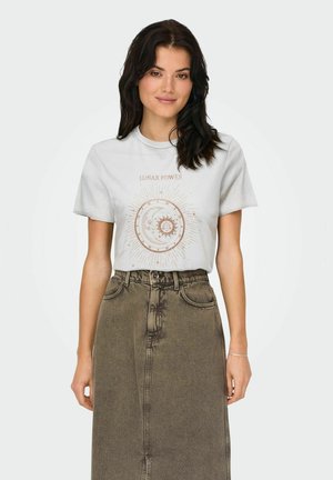 Camiseta gris claro con estampado de "LUNAR POWER", diseño circular de sol y luna, combinada con una falda de mezclilla marrón texturizada de cintura alta.