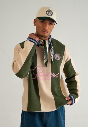 Zielono-beżowy sweter w paski z okrągłym dekoltem i różowym napisem. Uzupełniony wzorzystym szalikiem oraz kremową czapką z logo.