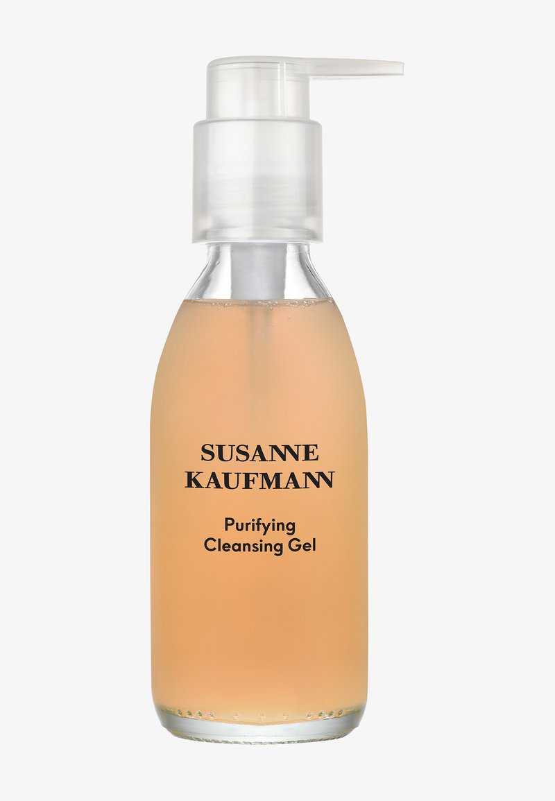 Przezroczysta butelka z pompką zawierająca jasno-pomarańczowy żel oczyszczający z etykietą Susanne Kaufmann Purifying Cleansing Gel na białym tle.
