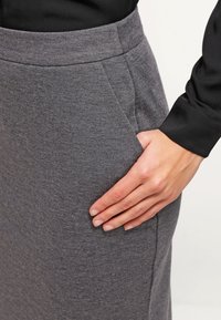 Grijze stretchrok met een gladde textuur, voorzien van een aansluitende tailleband en zijzakken. De stof is zacht en ademend, ideaal voor casual kleding.