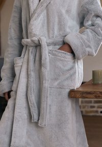 Lichtgrijze, zachte badjas met een sjaalkraag, ceintuur en twee voorzakken, met een zachte textuur en een ontspannen silhouet.